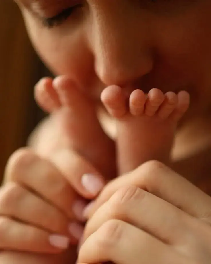 Mother kissing her newborn’s feet